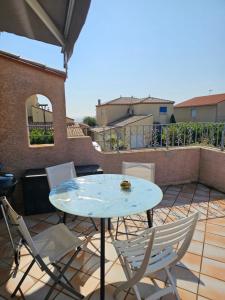 a patio with a table and chairs on a balcony at les 2 dauphins in Le Barcarès
