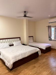 a bedroom with two beds and a ceiling fan at TSR Grand Hotel in Bhogāpuram