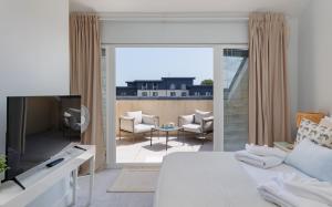a bedroom with a bed and a tv and a balcony at Seagrass in Sandown