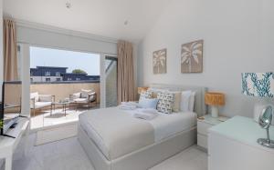 a white bedroom with a bed and a balcony at Seagrass in Sandown