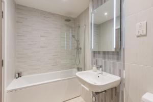 a white bathroom with a sink and a bath tub at Seagrass in Sandown +43 photos