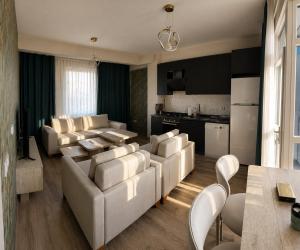 a living room with white furniture and a kitchen at Otel Grand Lark İstanbul in Istanbul