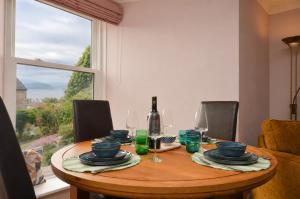 a dining room table with a bottle of wine and a window at Lochview at 33a in Gourock