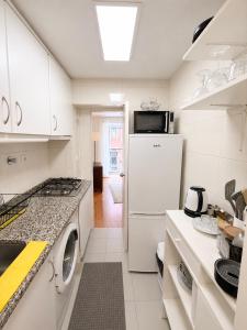 a white kitchen with a refrigerator and a microwave at Central Lisbon Apartment Santos Walk to Cais do Sodré in Lisbon