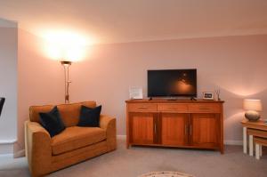 a living room with a chair and a television at Lochview at 33a in Gourock