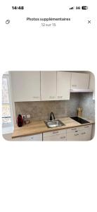 a kitchen with white cabinets and a sink at Chaleureux T1 avec Balcon in Vals-les-Bains