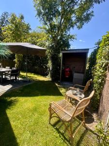 a patio with a table and chairs and an umbrella at Parc La Dune Dutch Lodge in Warmenhuizen