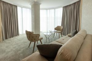 a living room with a couch and chairs and windows at Centralis Hotel in Haskovo