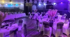 a room with white tables and chairs and purple lighting at The Windsor Hotel and Bar in Kirkcaldy