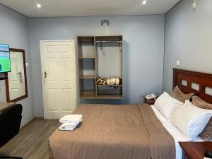 a bedroom with a bed with a mirror and a television at Nduna Legacy Lodge in Harare