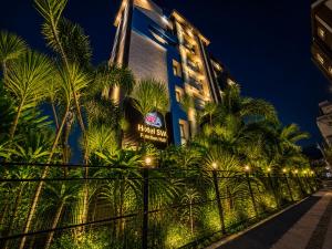 a building with palm trees in front of a fence at Hotel SVA in Visakhapatnam