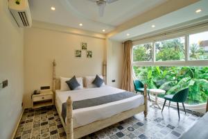 a bedroom with a bed and a large window at The Goa Courtyard by Forever stays in Arpora