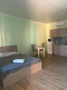 a bedroom with a bed and a table and a kitchen at МилаДэя in Kapchagay