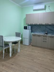 a kitchen with a table and a white refrigerator at МилаДэя in Kapchagay