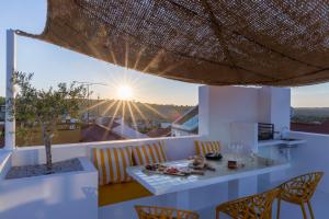 a dining room with a table and chairs and the sunset at DamnView Montargil Alentejo in Montargil +39 photos