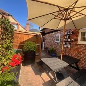 a patio with a wooden bench and an umbrella at Hunston Mill Self Catering Dog Stay For Free in Chichester