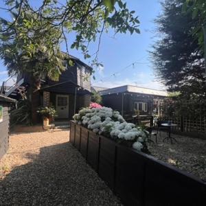 a fence with flowers in front of a house at Hunston Mill Self Catering Dog Stay For Free in Chichester