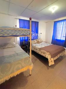 a bedroom with two bunk beds and blue curtains at Cabana Steps From The Beach - Pool & Beach Access in Nueva Gorgona