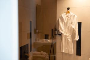 a bathroom with a white robe and a sink at Didimos Town Hotel in Reggio di Calabria +47 photos