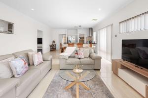 a living room with a couch and a table at 4 bedroom luxury modern home near the beach and parks in Alkimos