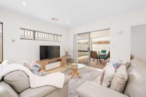 a living room with a couch and a tv at 4 bedroom luxury modern home near the beach and parks in Alkimos