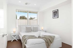 a white bedroom with a bed and a window at 4 bedroom luxury modern home near the beach and parks in Alkimos