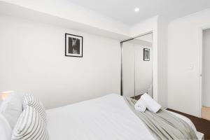 a white bedroom with a bed and a mirror at 4 bedroom luxury modern home near the beach and parks in Alkimos