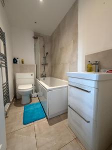 a bathroom with a tub and a toilet and a sink at Serene 2-BDR Maisonette in Wolverhampton
