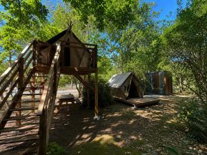 a tree house with a swing and a tent at Camping Le Capdeville in Carcans