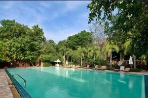 a large swimming pool with blue water and trees at Fairtex Residence Pattaya in North Pattaya