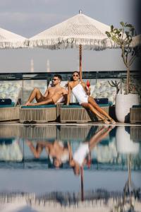 two men laying on lounge chairs next to a swimming pool at Novotel Abu Dhabi Gate in Abu Dhabi