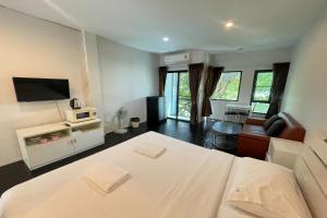 a bedroom with a white bed and a living room at Fairtex Residence Pattaya in North Pattaya