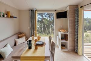 a dining room with a table and a couch at Camping les Chalands Fleuris in Saint-André-des-Eaux