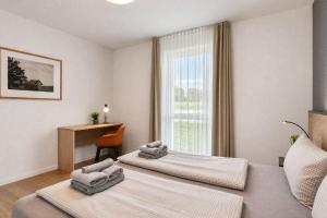 two beds in a room with a desk and a window at Ferienwohnung Grünfink 04 im Wreecher Idyll Rügen by ruyastay in Putbus