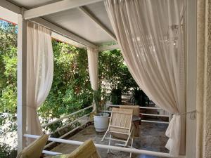 a porch with curtains and a table and a chair at Pension Alkistis in Tolo