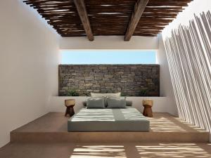 a bedroom with a bed and a brick wall at Oroséa Paros - Adults Only, Autograph Collection in Naousa +142 photos