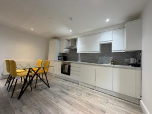 a kitchen with white cabinets and a table and chairs at Serene 2-BDR Maisonette in Wolverhampton +4 photos
