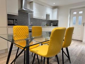 a dining room with a glass table and yellow chairs at Serene 2-BDR Maisonette in Wolverhampton