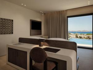a bedroom with a desk and a bed with a view at Oroséa Paros - Adults Only, Autograph Collection in Naousa