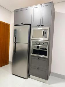 a kitchen with a stainless steel refrigerator and a microwave at O mais charmoso do centro in Sinop