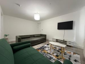 a living room with a green couch and a flat screen tv at Serene 2-BDR Maisonette in Wolverhampton