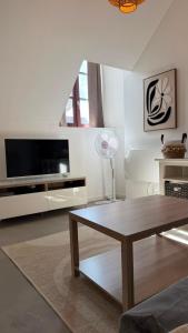 a living room with a table and a tv at Le Cœur de Saint-Aignan in Saint-Aignan