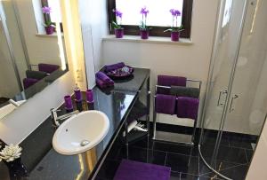 Un baño con lavabo y ducha con toallas moradas. en Bambus, en Leipzig