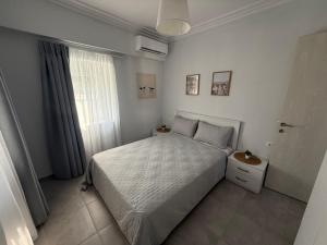 a white bedroom with a bed and a window at Mpampis House in Ammouliani