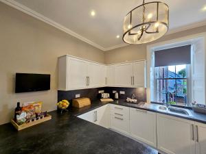 a kitchen with white cabinets and a sink and a chandelier at No. 41 Town House in Inverness +13 photos