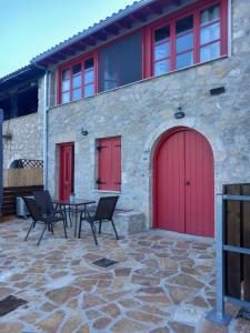 a building with red doors and a table and chairs at Sweet Red Home in Asprogerakata