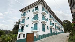 a white building with green shuttered windows at Comodo aparta estudio en Jerico Antioquia in Jericó