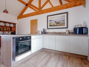 a kitchen with white cabinets and a black oven at Westhills Courtyard - The Loft in Winster
