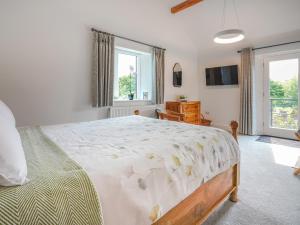 a bedroom with a large bed and a window at Westhills Courtyard - The Loft in Winster +6 photos