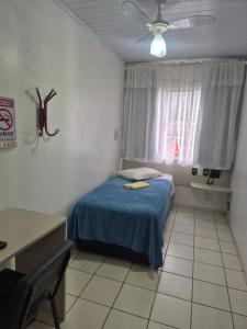 a small bedroom with a blue bed and a window at Hotel Eduardo's in Rio do Sul